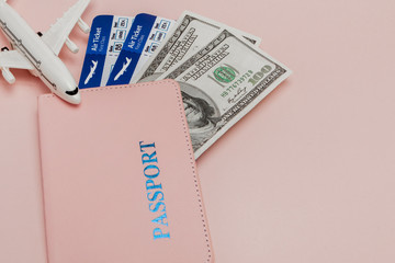Passport, dollars, plane and air ticket on a pink background. Travel concept, copy space