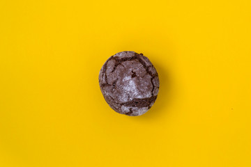 Flat chocolate marble cookies lay on a yellow background. Chocolate cookie shot.