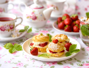 Profiteroles with strawberries on the summer table
