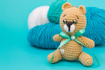 A brown knitted bear sits on a pink background, behind it is a ball of pink and yellow yarn, and an orange knitted hare stands behind the yarn. There is a place for text.