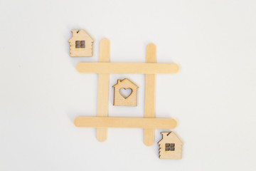 Three wooden houses lie in a row in the game of tic-tac-toe, in a grid on a white background. Concept home, cozy home