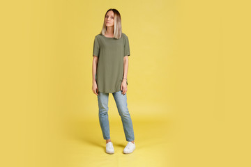 Portrait of a sad young slim girl in casual clothes on a yellow background. Beautiful girl is unhappy with the relationship with her boyfriend. Copyspace