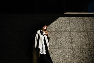 beautiful girl in coat with scarf walks on city street, portrait of woman resting outdoors