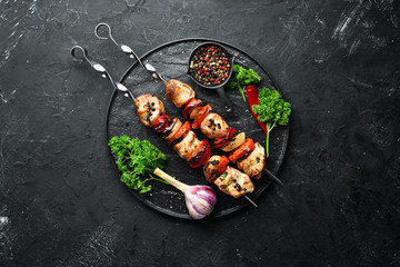 Chicken shish kebab with onions and tomatoes. Barbecue. On a black background. Top view. Free space...