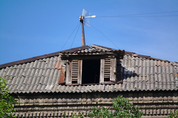 old broken attic window of a house with a rooftop antenna