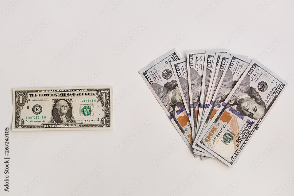 Wall mural top view of a banknote of one dollar and a row of hundred dollar banknotes at white background, isol