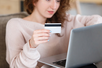 Close up shot of womans hands holding laptop pc and credit card, using online banking application. Selective focus. Online shopping concept