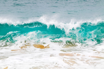 Blue and aquamarine color sea waves and yellow sand  with white foam. Marine beach background.