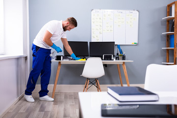 Janitor cleaning white desk in office