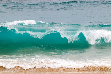 Blue and aquamarine color sea waves and yellow sand  with white foam. Marine beach background.