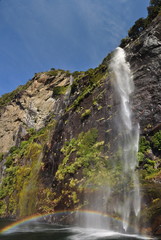 Waterfall in Milford Sound, New Zealand with a rainbow in the water spray 