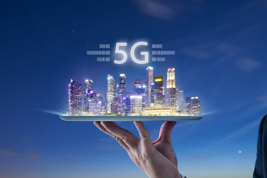 Waiter hand holding an digital tablet with Smart city with smart services and icons, internet of things, networks and augmented reality concept , night scene .