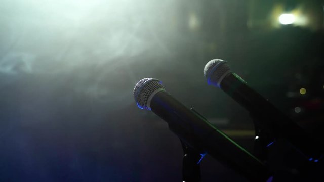 Close-up of two free microphones in a dark smoky room.