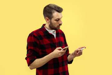 Half-length close up portrait of young man in shirt on yellow background. The human emotions, facial expression concept. Front view. Trendy colors. Negative space. Paying by phone with card.