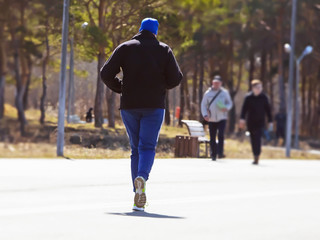 adult on cardio jogging in city park on a sunny day
