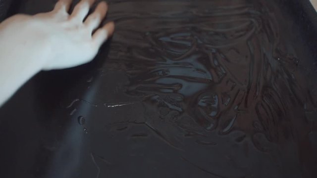 sunflower oil is poured into the pan, a woman's hand spreads it across the entire pan.