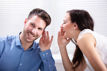 Woman Whispering Secret To Handsome Man In His Ear