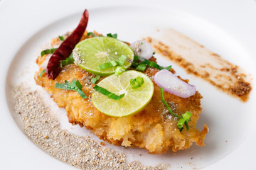 Spicy salad with fried chicken in white dish on table.