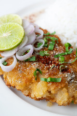Spicy salad with fried chicken and rice in white dish on table.