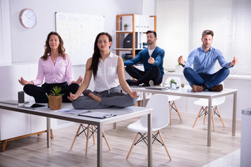 Businesspeople Meditating In Office - Powered by Adobe