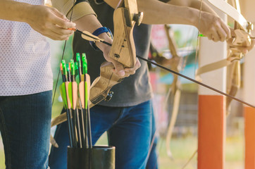 Tourists try to use a bow and arrow and shoot at a target in the amusement park.