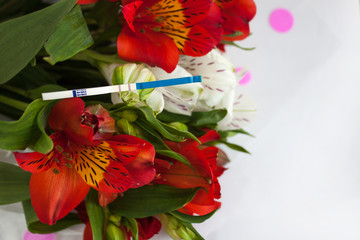 Positive pregnancy test with a bouquet of alstroemeria flowers