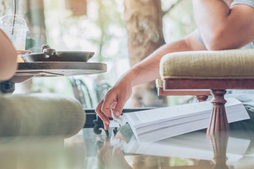 Asian man read a book in a coffee shop.