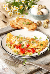 Homemade breakfast omelette with tomatoes, cheese and herbs
