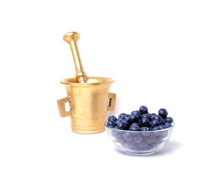 Food as medicine for health.  Glass bowl of blueberries with a vintage mortar and pestle isolated on white background