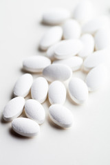 Pile of white drug pills laying on white background.