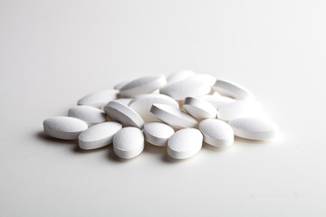 Fototapeta na wymiar Pile of white drug pills laying on white background. Medical concept.