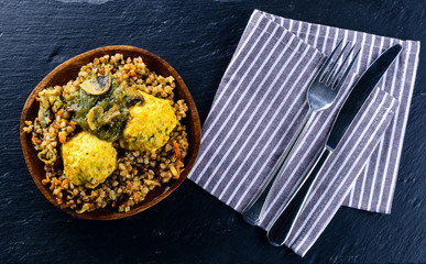 Chicken cutlets with buckwheat porridge on blue plate on wooden table.