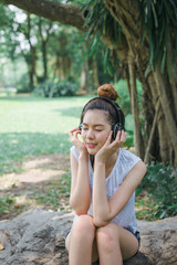 beautiful woman sit in the garden and relaxing by listen to music from stereo headphones. with copy space for text