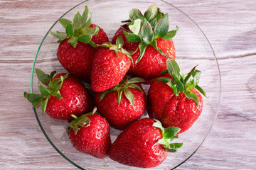 Red juicy strawberry lies on a saucer. Seasonal berries.
