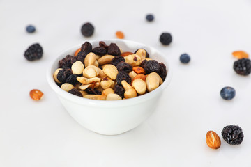 Nuts and berries are scattered on the table. nuts are in the plate.