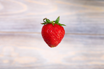 Red juicy strawberries hanging in the air. Seasonal berries.
