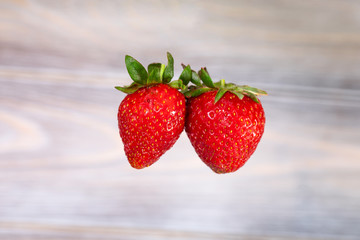 Red juicy strawberries hanging in the air. Seasonal berries.
