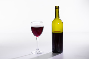 Bottle and glass with red wine on white background