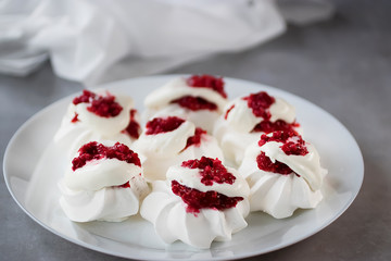 Meringues with whipped cream and raspberry sauce on a white plate. Dessert Pavlova.