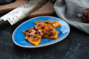 Grilled pumpkin with pomegranate, onion and honey. Baked with white wine pumpkin on the kitchen table.