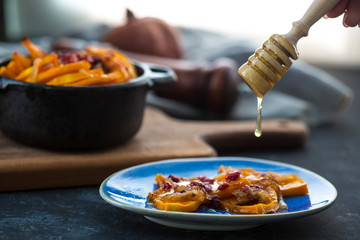 Grilled pumpkin with pomegranate, onion and honey. Baked with white wine pumpkin on the kitchen table.