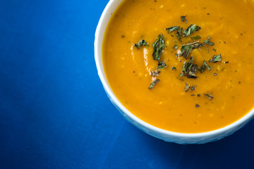 Pumpkin cream soup. Fresh soup with herbs on a background, Autumn concept. Tasty healthy food.