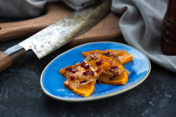 Grilled pumpkin with pomegranate, onion and honey. Baked with white wine pumpkin on the kitchen table.