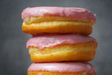 Closeup stack of pink donuts on gray background