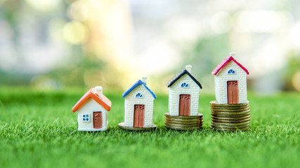 Money growth represented by coin towers and house on each top of the coin stack.