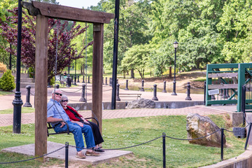 A beautiful senior couple enjoys the day at a park, sitting in a chair swing, on a spring day.