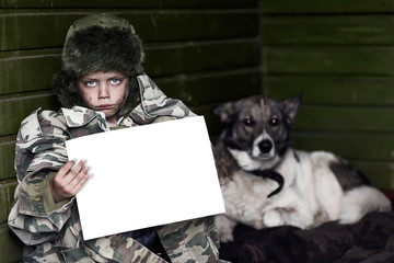 boy in camouflage and a hat with a dog holding a white sheet of paper