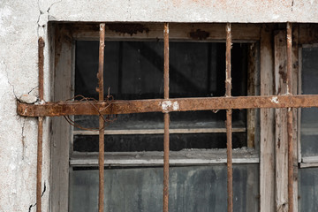 Broken glass in a window with a rusty lattice
