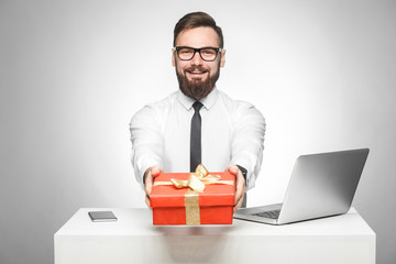 Take present! Portrait of happy young boss in in white shirt and black tie are sitting in office...