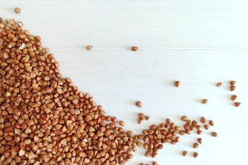 Organic buckwheat groats  a white  wooden background. Ingredient for healthy breakfast. Top view, flat lay, copy space for text.